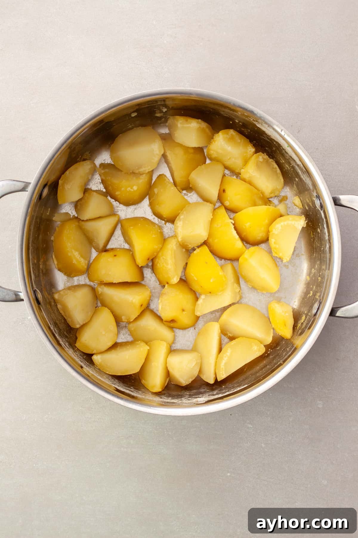 Partially cooked potatoes drained in a pot getting ready to be roasted.