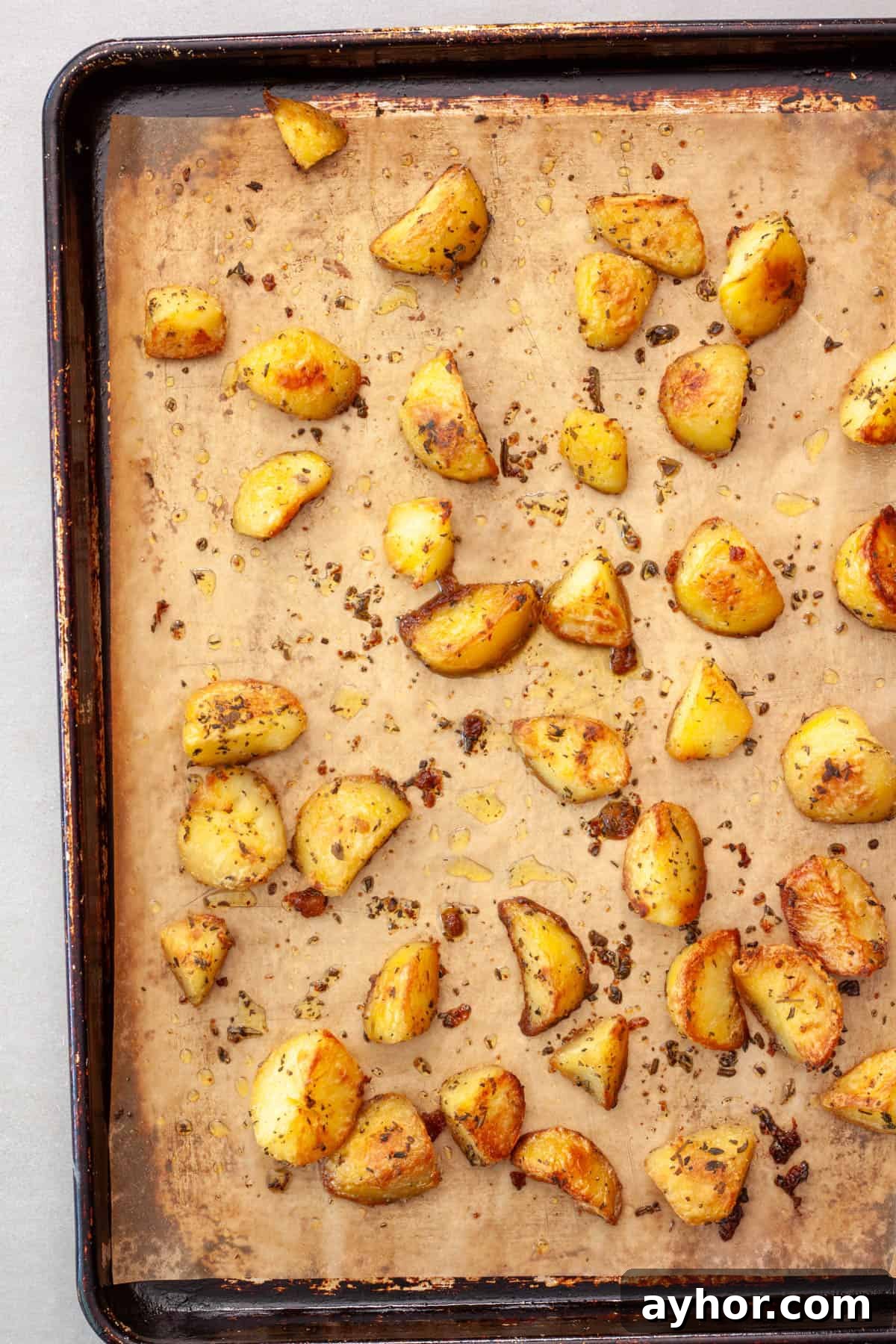 Crispy herb roasted yukon gold potatoes fresh out of the oven on a parchment lined baking sheet.