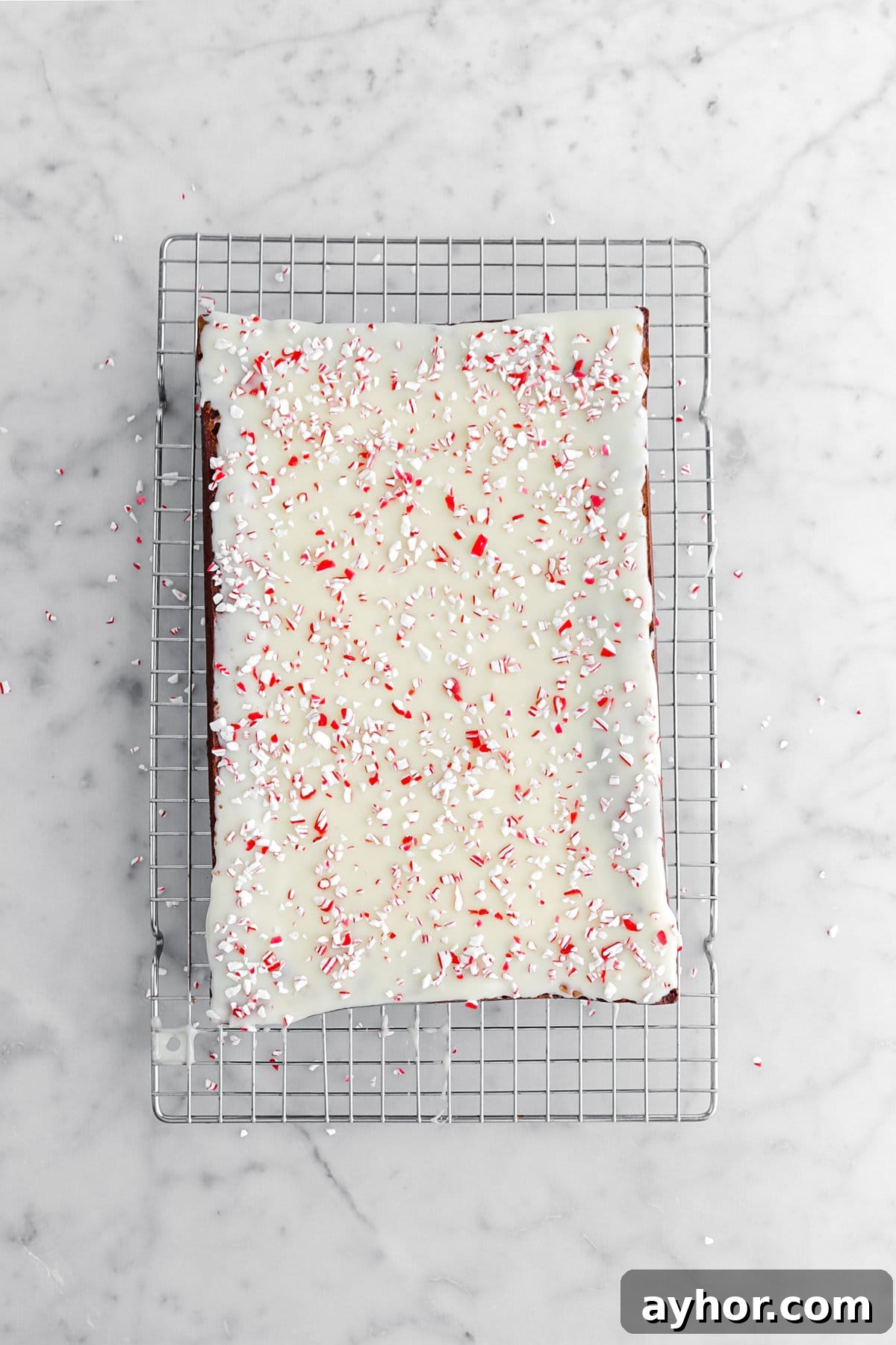 crushed candy canes on top of white chocolate ganache on brownies on wire cooling rack.