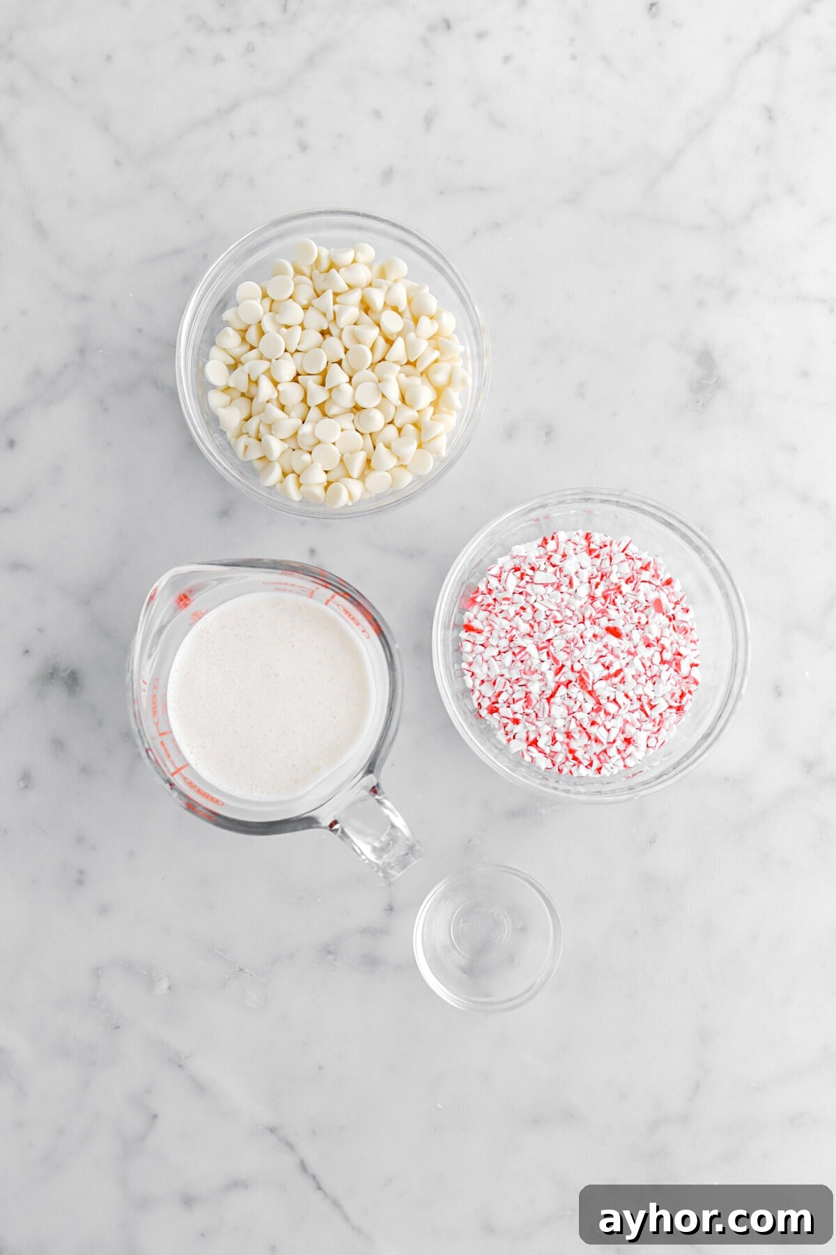 white chocolate chips, cream, crushed candy canes, and peppermint extract on marble surface.