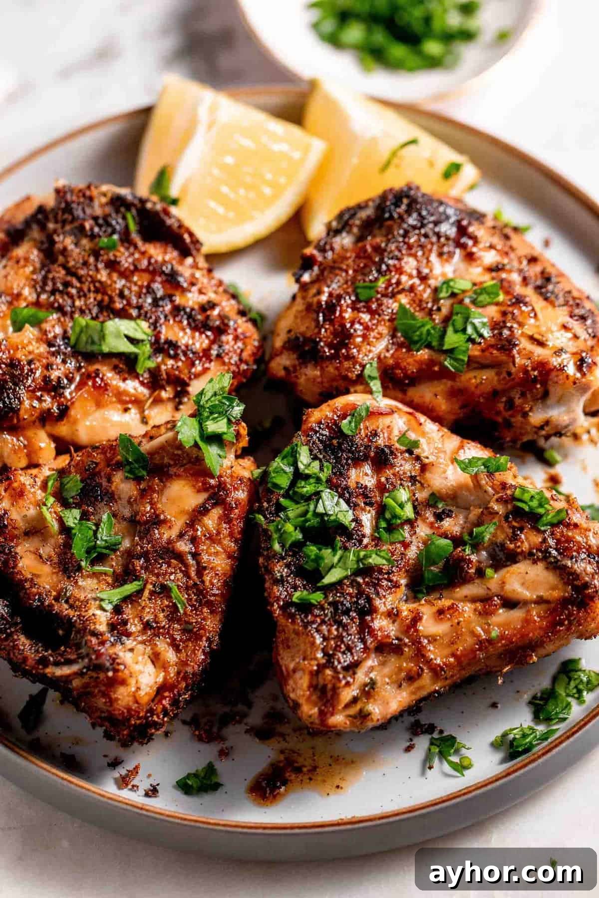 Juicy golden brown chicken garnished with fresh parsley and lemon wedges.