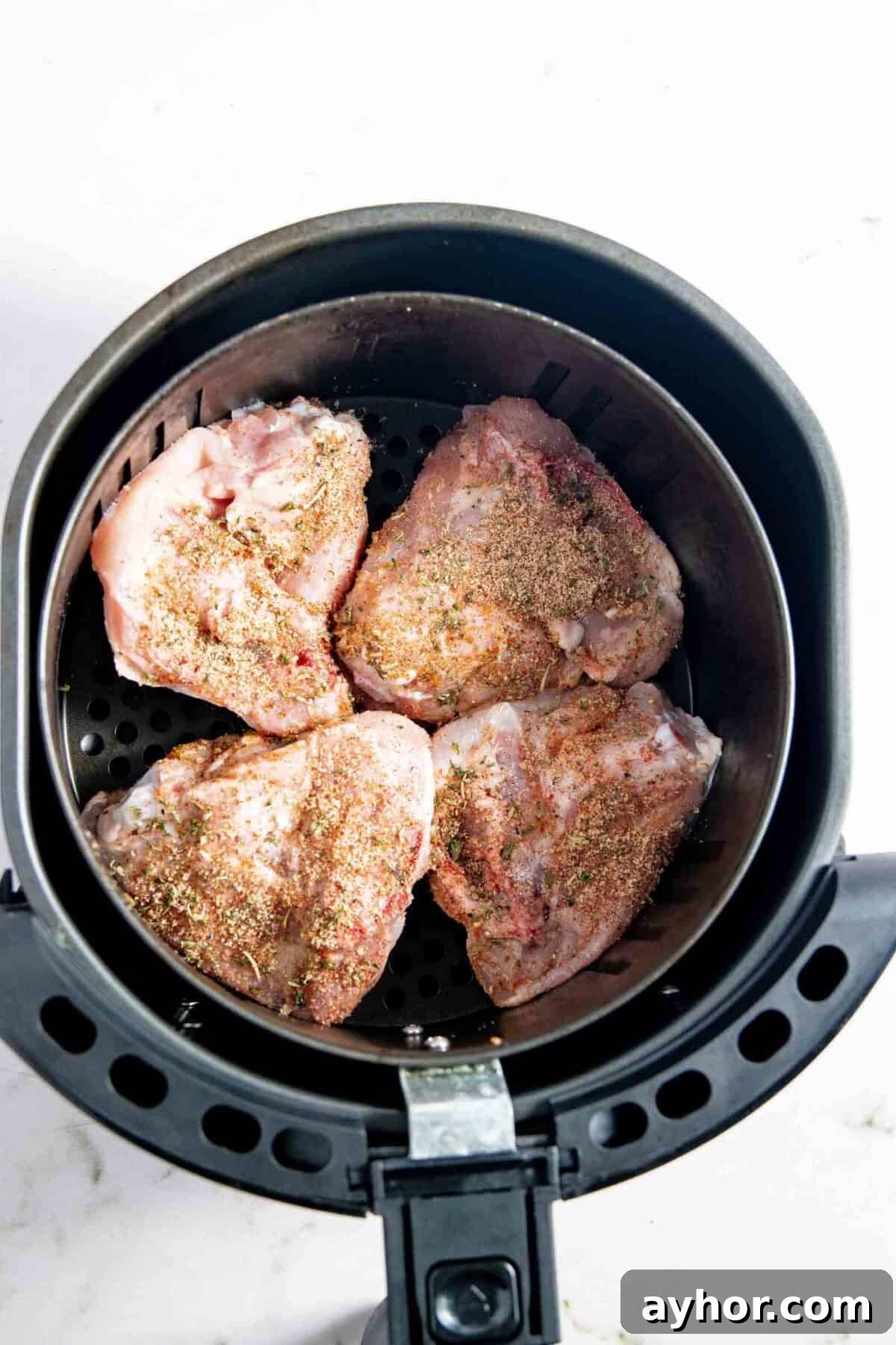 Raw chicken placed in the air fryer basket.