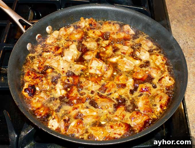 Sticky Orange Chicken Recipe bubbling in a pan with sauce