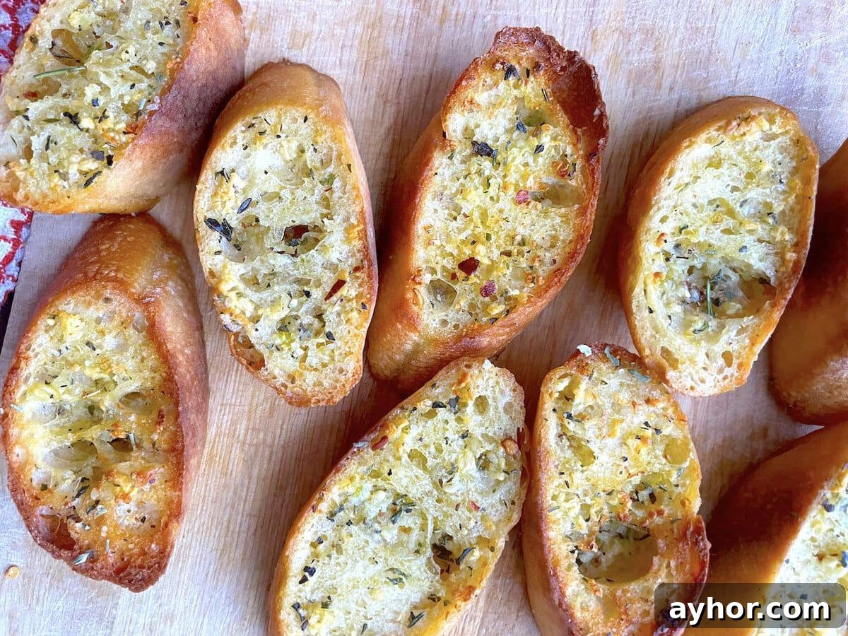 Quick Garlic Toast Recipe for Crispy, Flavorful Slices 2 Slices of garlic toast with Italian seasoning on a wood cutting board.