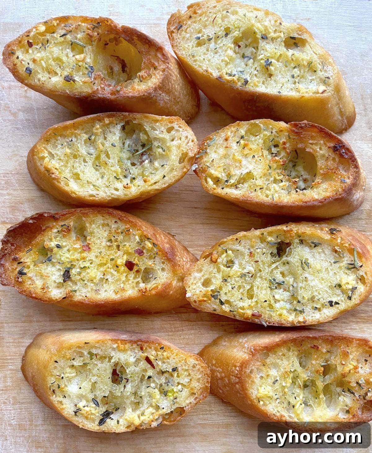 Quick Garlic Toast Recipe for Crispy, Flavorful Slices 10 Slices of garlic toast with Italian seasoning on a wood cutting board.