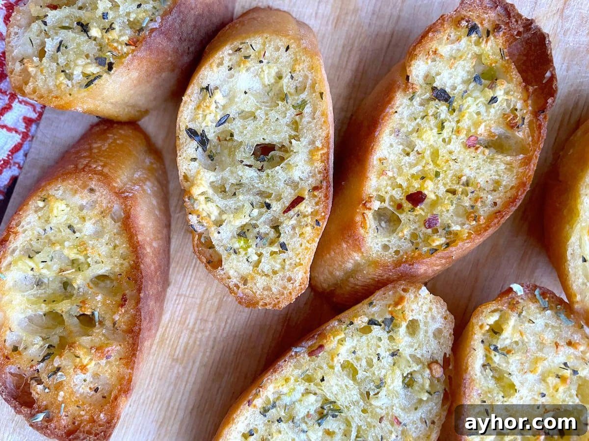 Quick Garlic Toast Recipe for Crispy, Flavorful Slices 15 Slices of garlic toast topped with Italian seasoning on a wooden board.