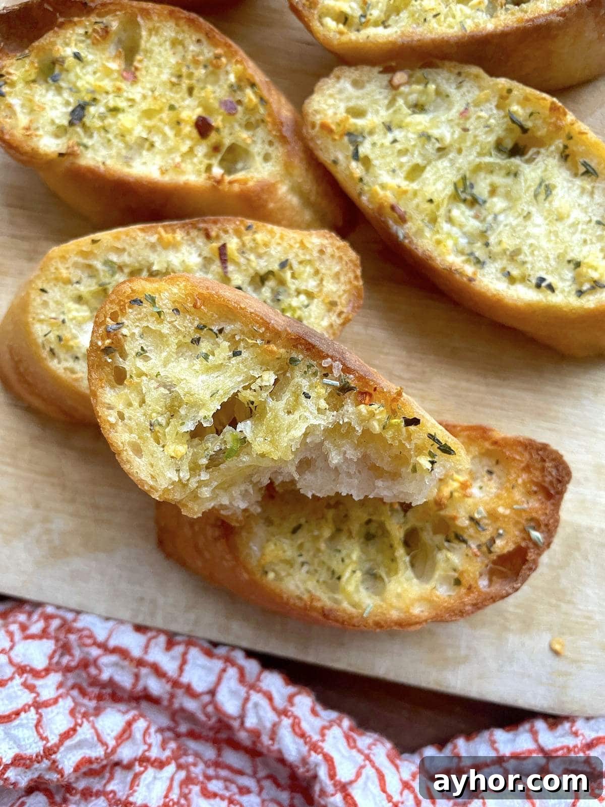 Quick Garlic Toast Recipe for Crispy, Flavorful Slices 8 Slices of garlic toast on a cutting board with a bite taken out of one of the pieces.