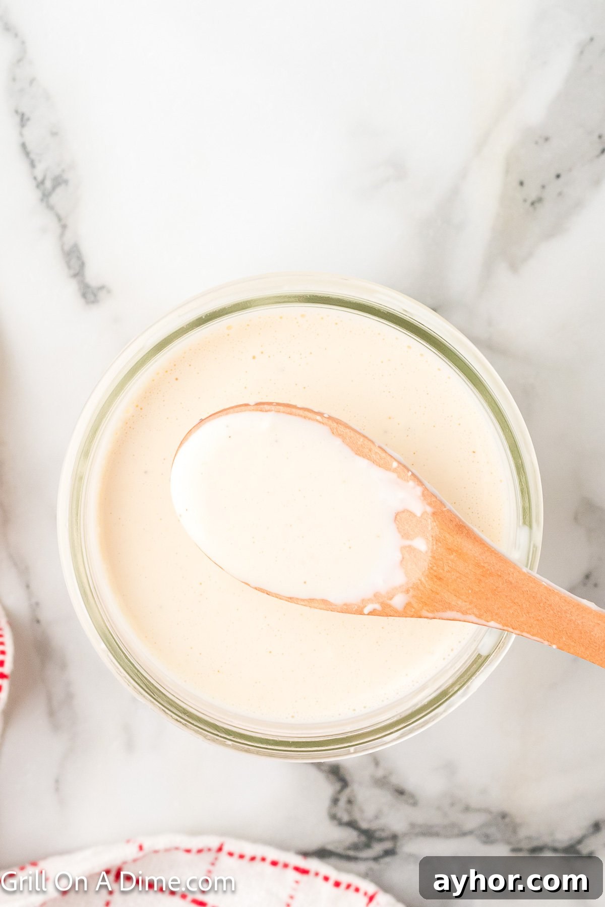 Alabama White BBQ Sauce Recipe: Tangy Homemade Chicken & Pork Glaze 8 White sauce in a jar with a wooden spoon on top