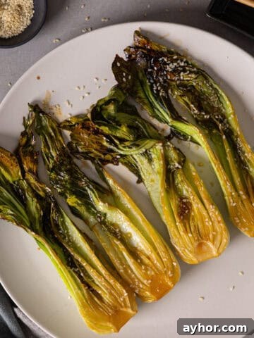 A platter of roasted bok choy lightly browned and garnished with sesame seeds.