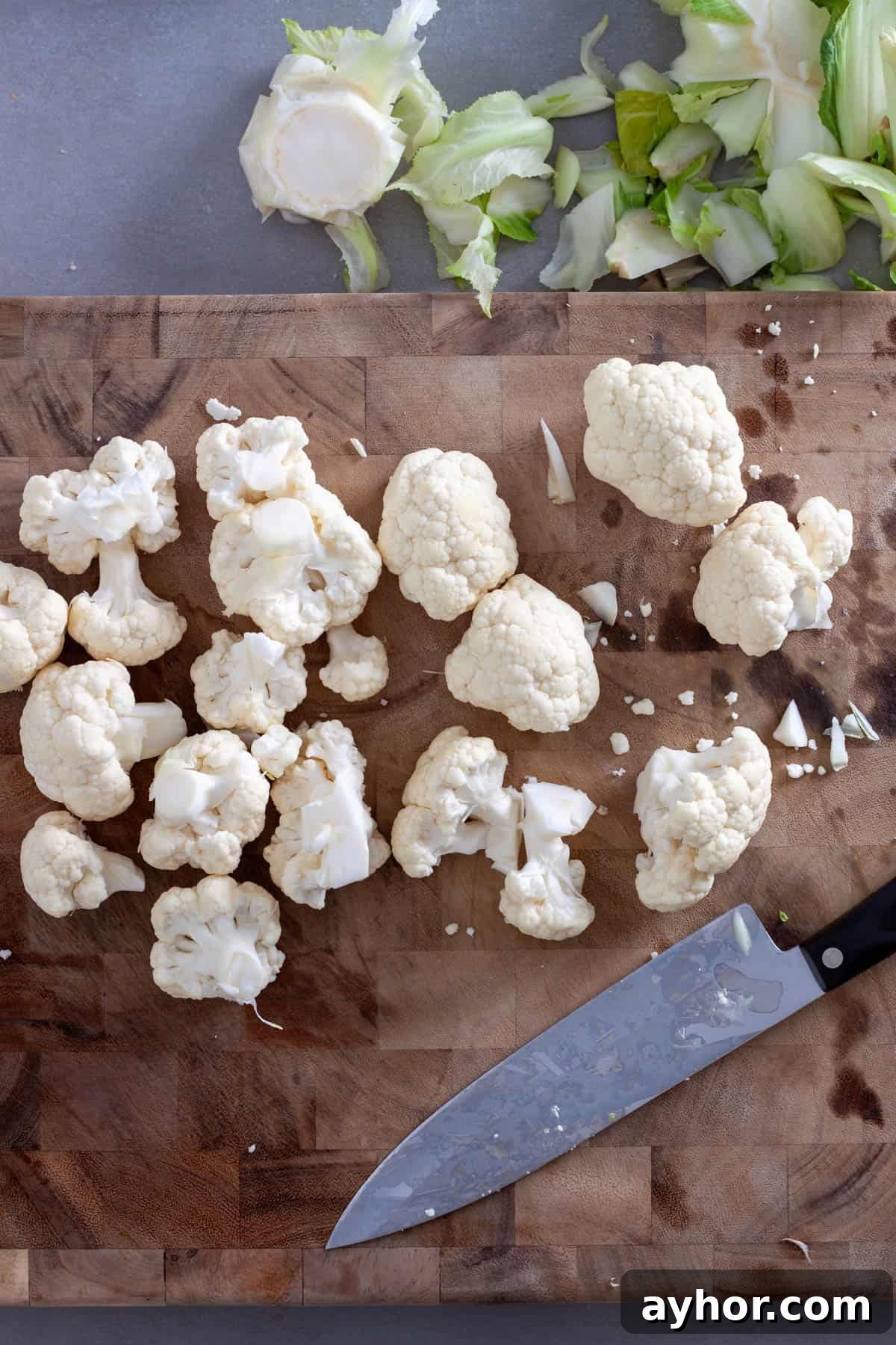 Chopped cauliflower florets on a butcherblock cutting board.
