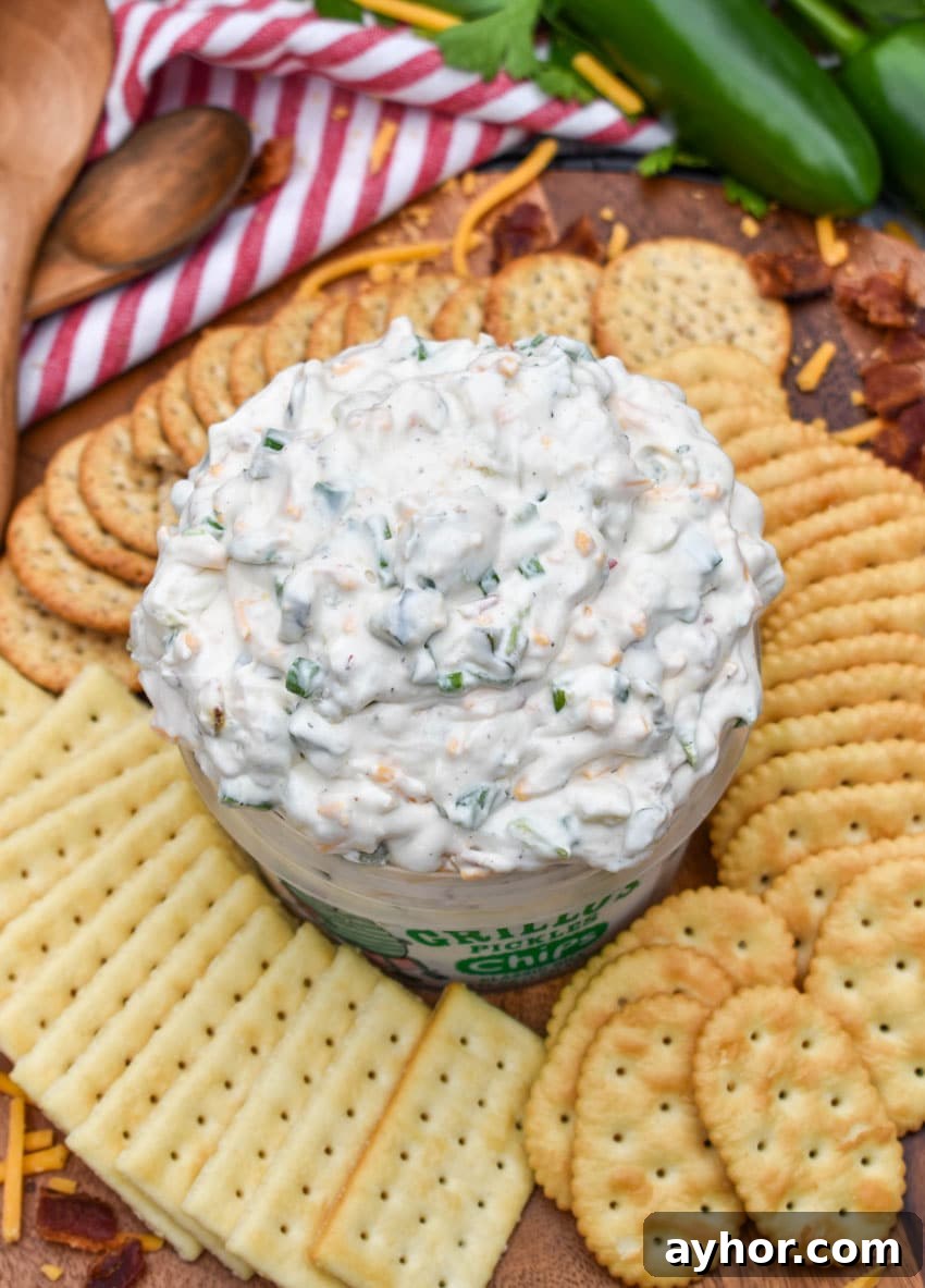 a plastic tub filled with grillo's dill pickle dip surrounded by crackers