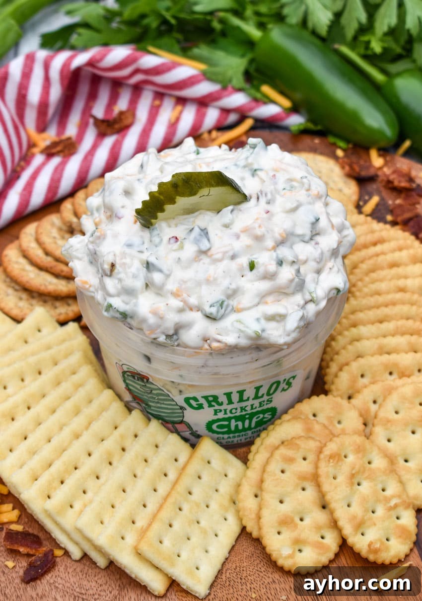 a plastic tub filled with grillo's dill pickle dip surrounded by crackers