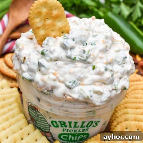 a plastic tub filled with grillo's dill pickle dip surrounded by crackers