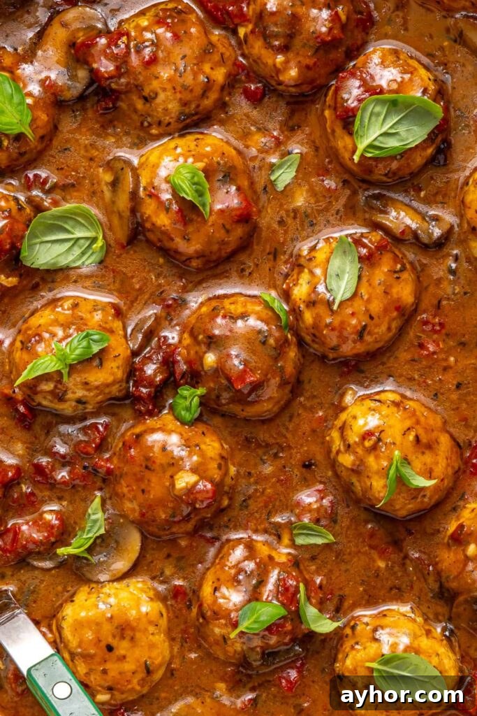 close-up of Marry me chicken meatballs with basil garnish in creamy sauce