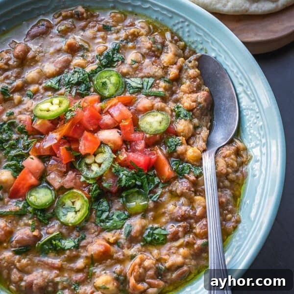 Levantine Ful Medames: Classic Chickpea & Fava Bean Stew Recipe 14 Bowl of mashed fava and chickpeas topped with diced tomatoes and parsley.