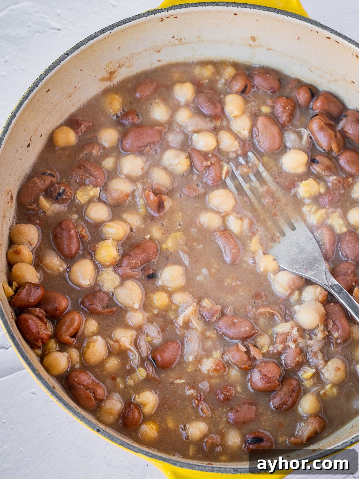 Levantine Ful Medames: Classic Chickpea & Fava Bean Stew Recipe 5 Mashing the beans with a fork.