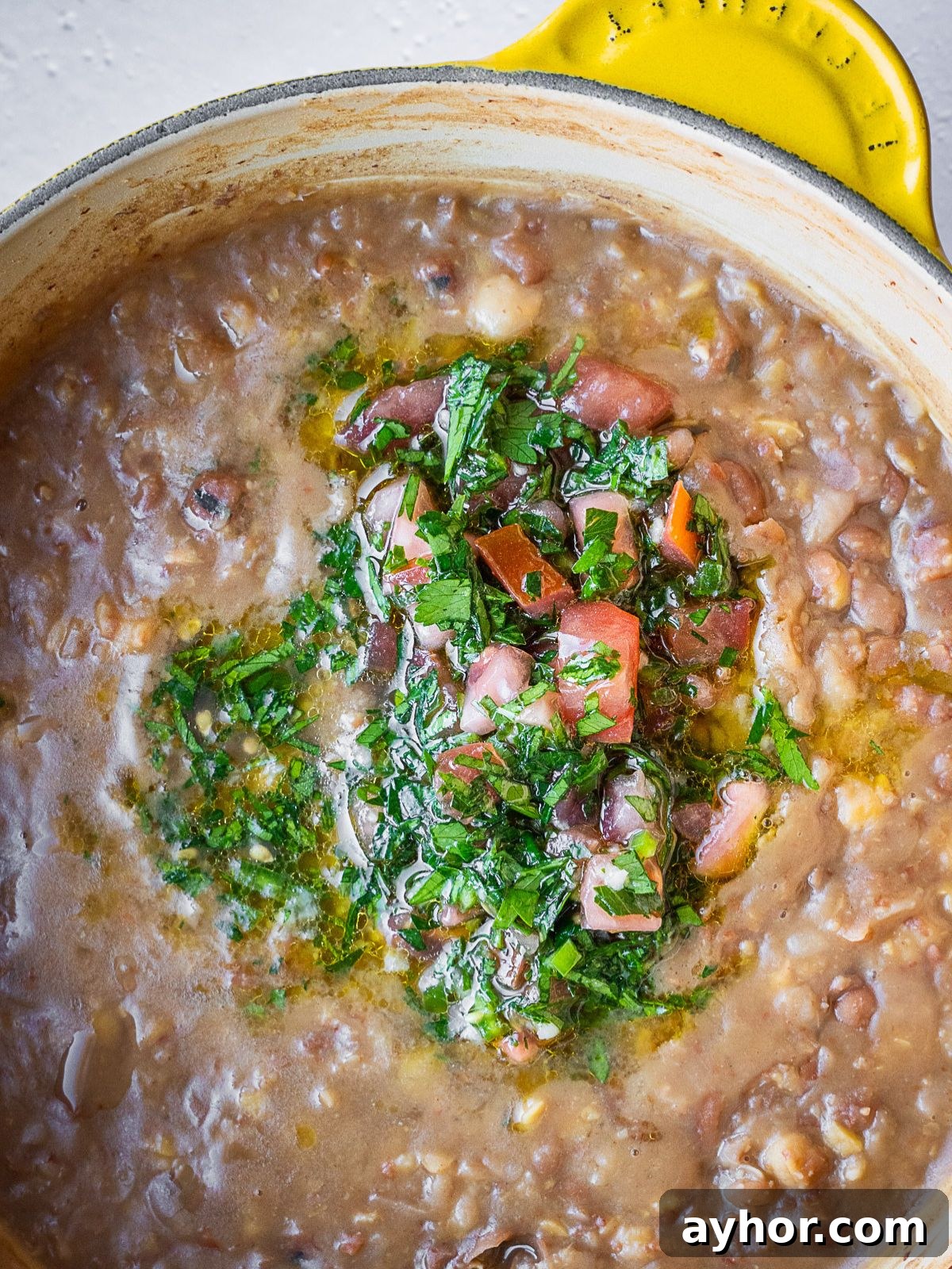 Levantine Ful Medames: Classic Chickpea & Fava Bean Stew Recipe 7 Adding the dressing to the pot of beans.