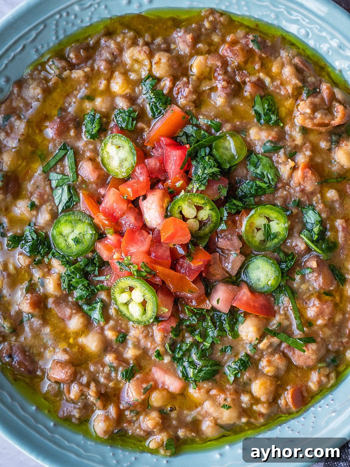 Levantine Ful Medames: Classic Chickpea & Fava Bean Stew Recipe 8 Bowl of ful medames garnished with more dressing.