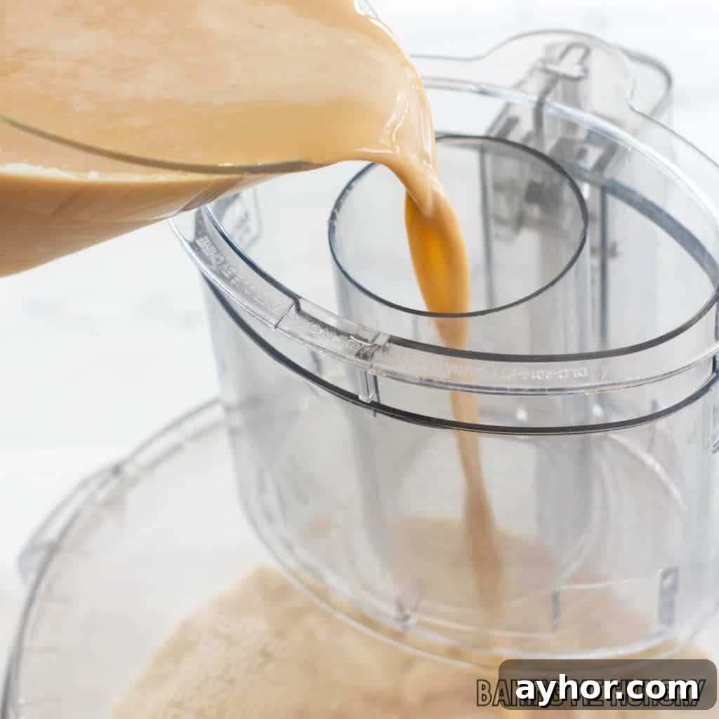 creamy espresso mixture being poured into food processor shoot