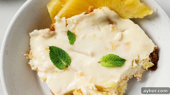 A serving of Crushed Pineapple Dessert in a white plate with sliced pineapples on the side.