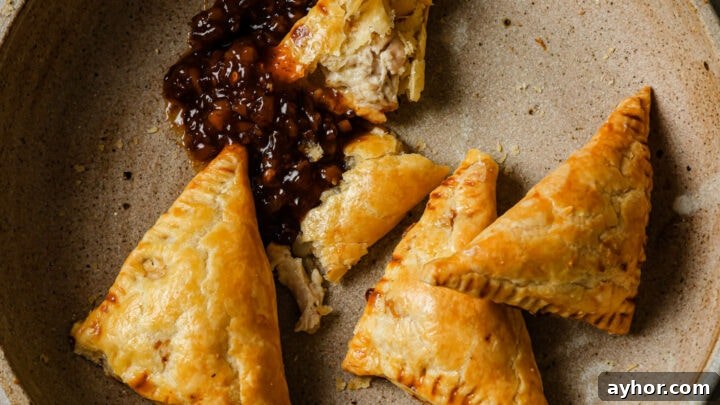 A bowl of partially eaten Chicken Puff Pastires with tamarind chutney.