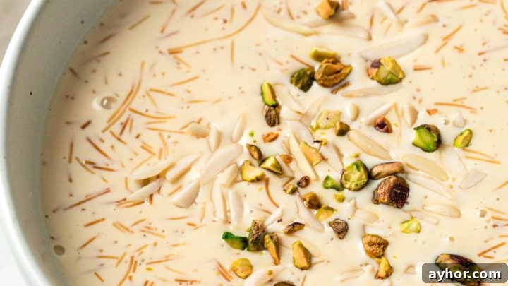 A large bowl with sheer khurma served with spoons and nuts in small bowls
