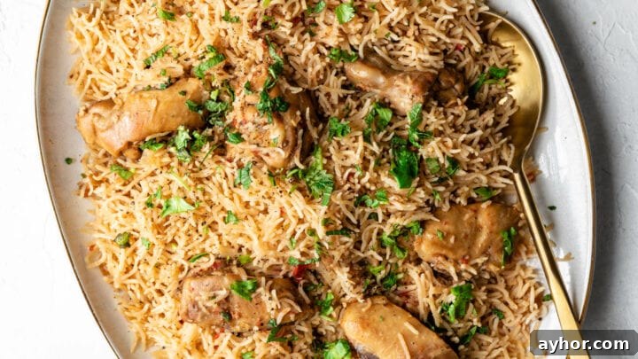 Chicken pulao on a platter with a golden spoon and raita