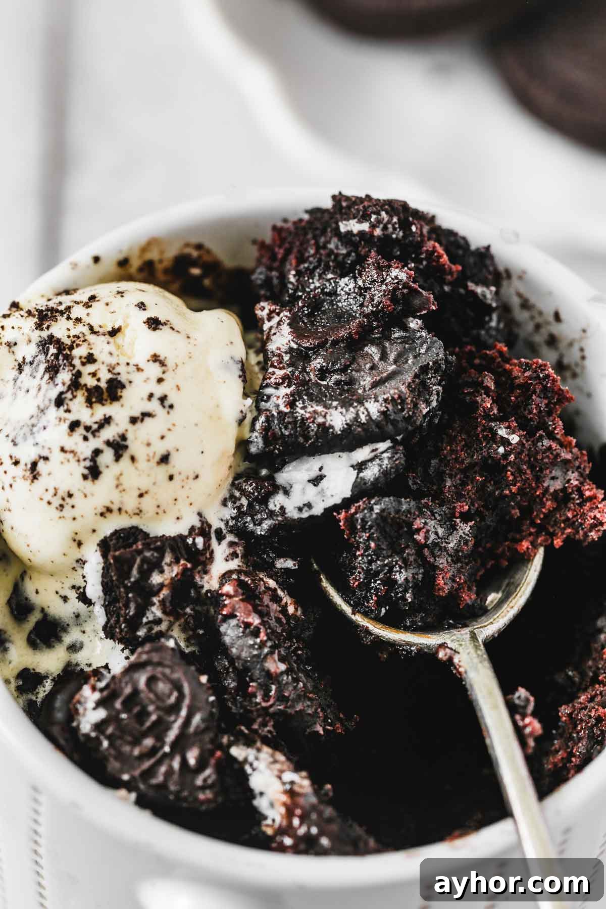 spoonful of gooey oreo mug cake topped with vanilla ice cream