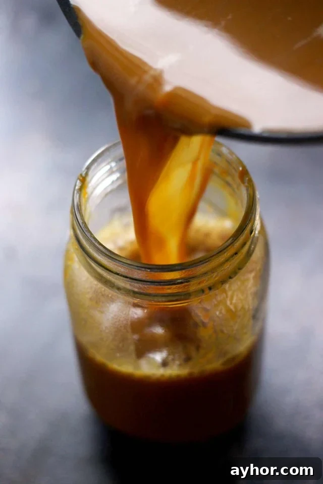 Healthy Vegan Pumpkin Spice Latte Being Poured into a Mason Jar Stnaind on the Table