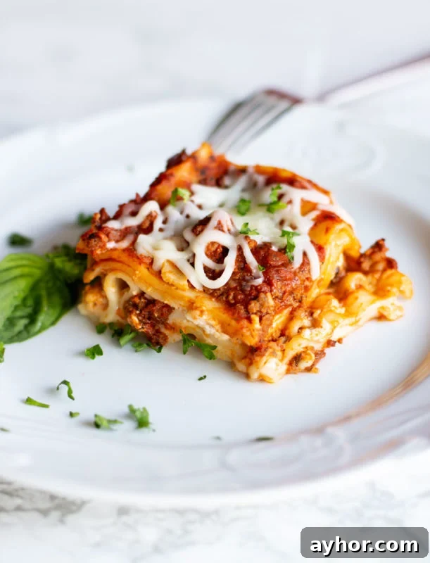 Classic Homemade Lasagna Recipe for Rich, Cheesy Layers 2 White plate containing a slice of layered lasagna with Italian meat sauce and 4 cheeses. Topped with basil.