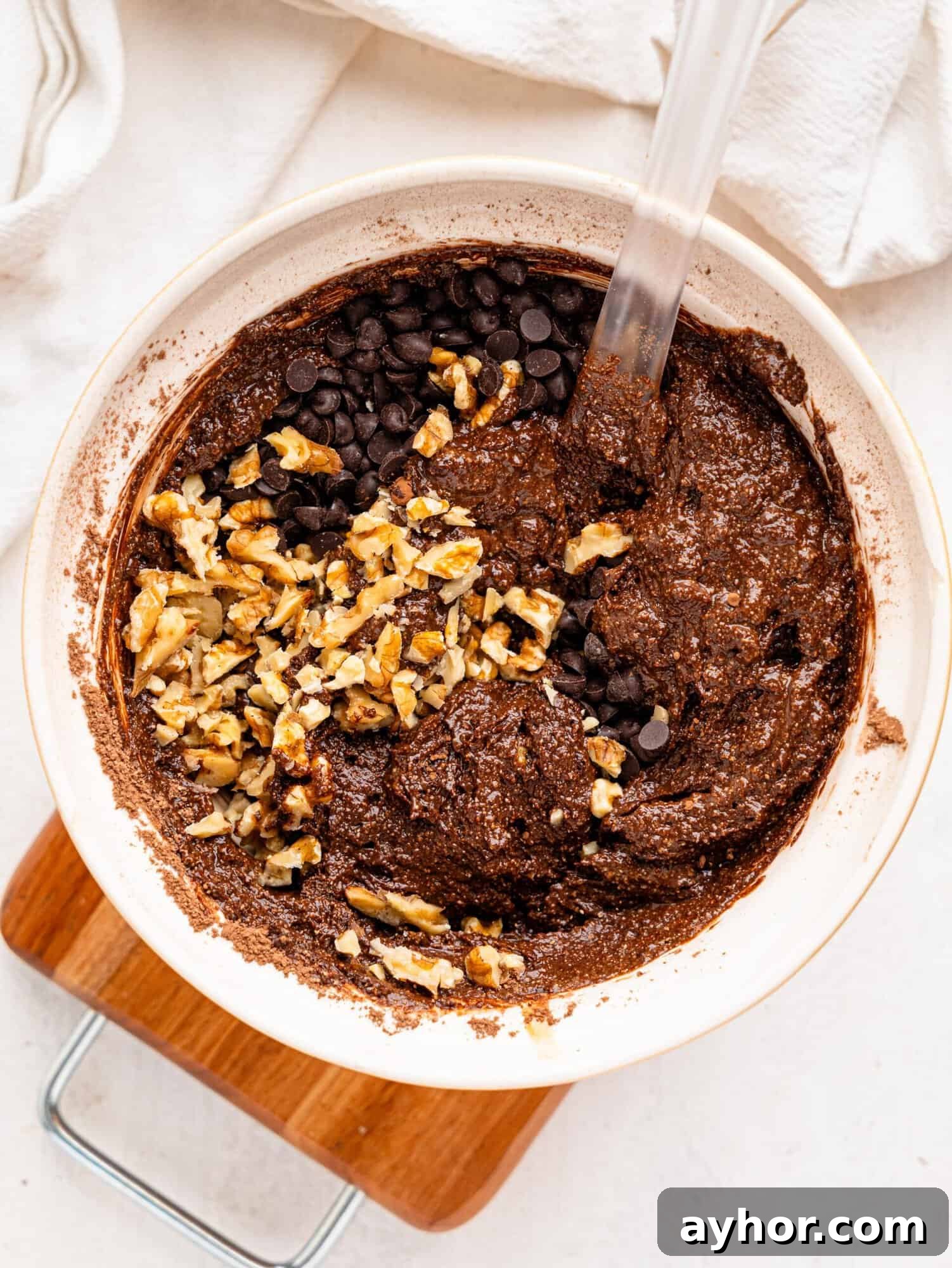 Cottage cheese brownie batter in a mixing bowl with walnuts and chocolate chips.