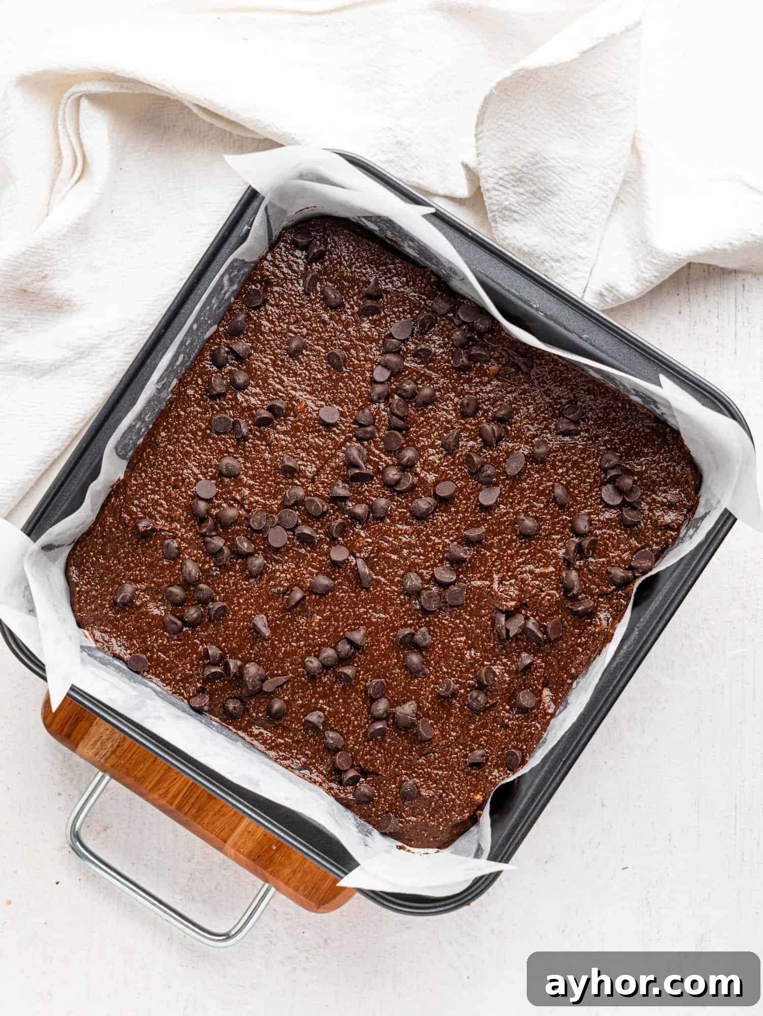 Cottage cheese brownie batter in a baking tin with chocolate chips on top.