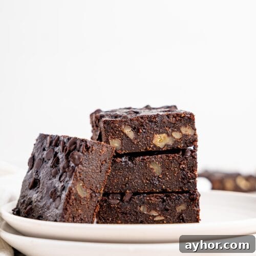 Four brownies on a white plate.