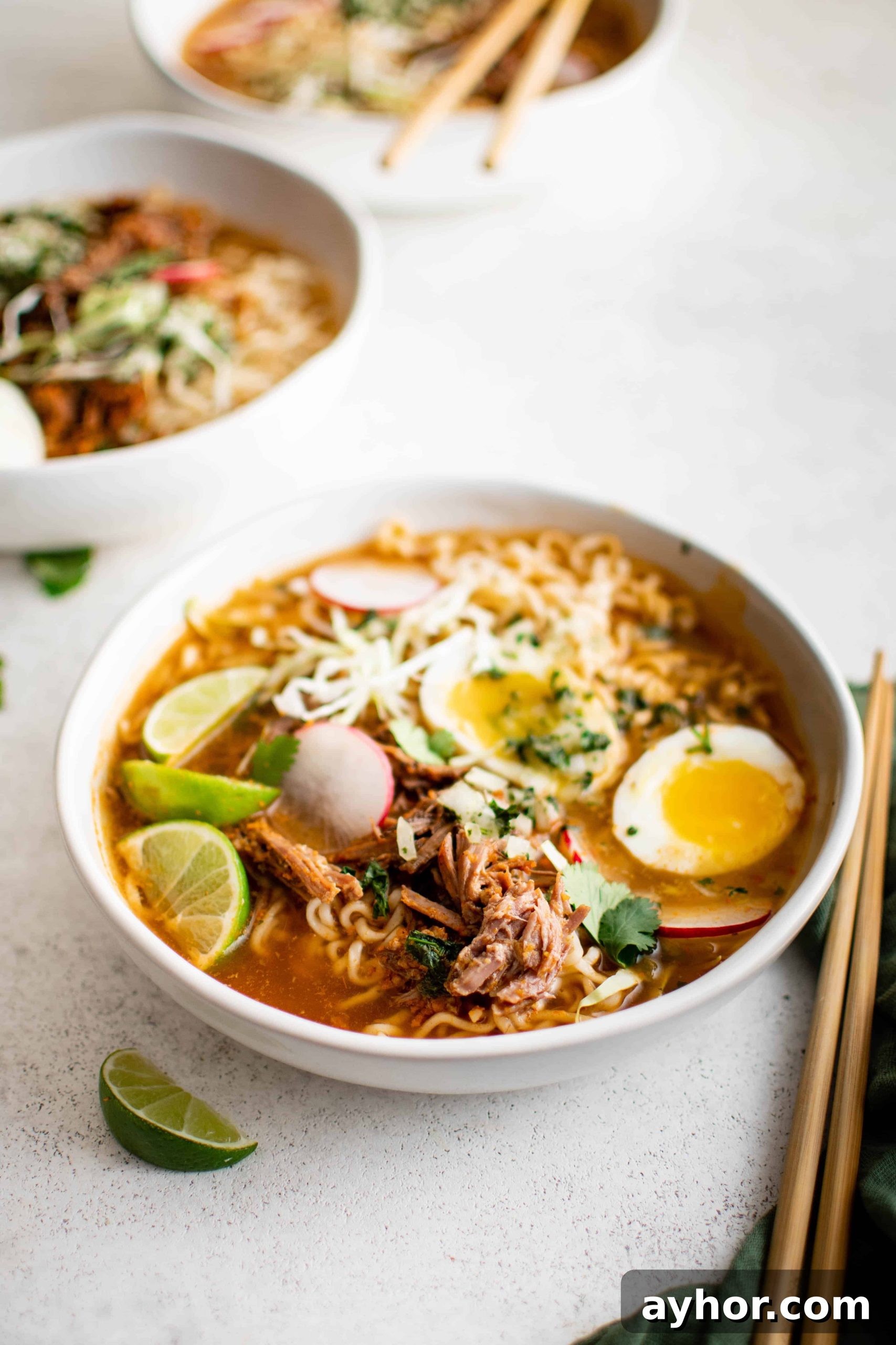 Birria Ramen Recipe: Flavorful Mexican-Style Beef Ramen 8 Large white serving bowl filled with birria ramen soup garnished with sliced radish, cilantro, soft boiled eggs, and salsa.