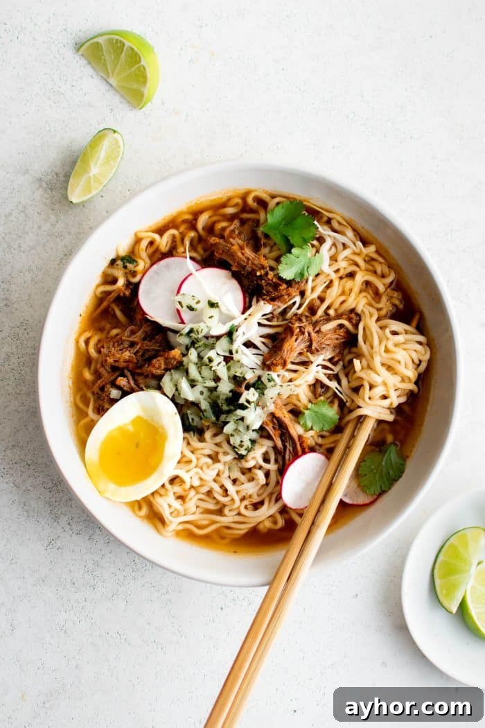 Birria Ramen Recipe: Flavorful Mexican-Style Beef Ramen 9 Large white serving bowl filled with birria ramen soup garnished with sliced radish, cilantro, soft boiled eggs, and salsa.