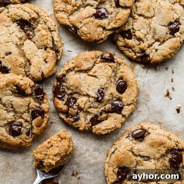Miso toffee browned butter chocolate chip cookies on a parchment paper-lined baking tray with a spoonful of miso.