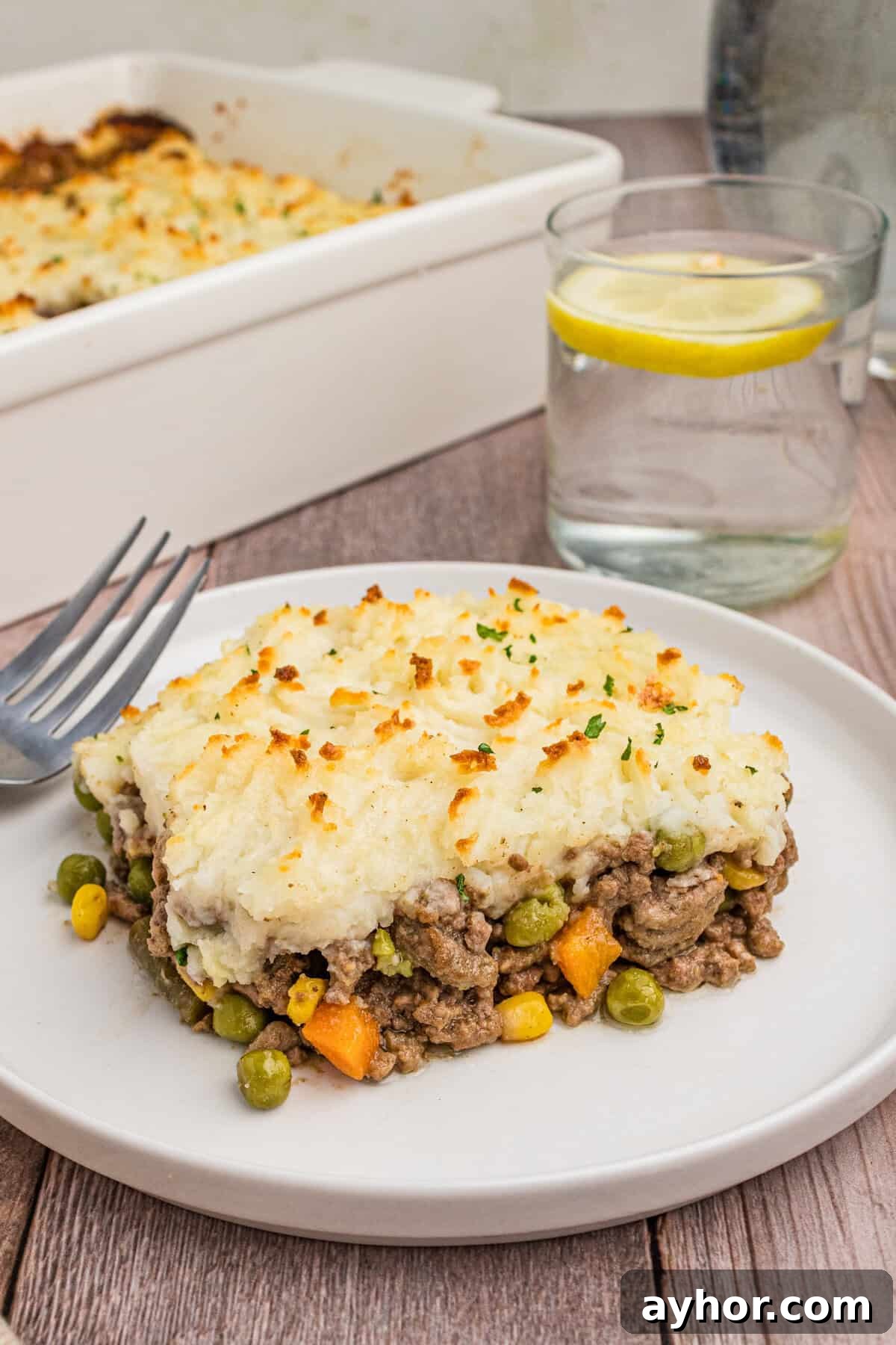 A plated slice of cottage pie on a white dish, showcasing the layered mashed potatoes and beef filling with vegetables.