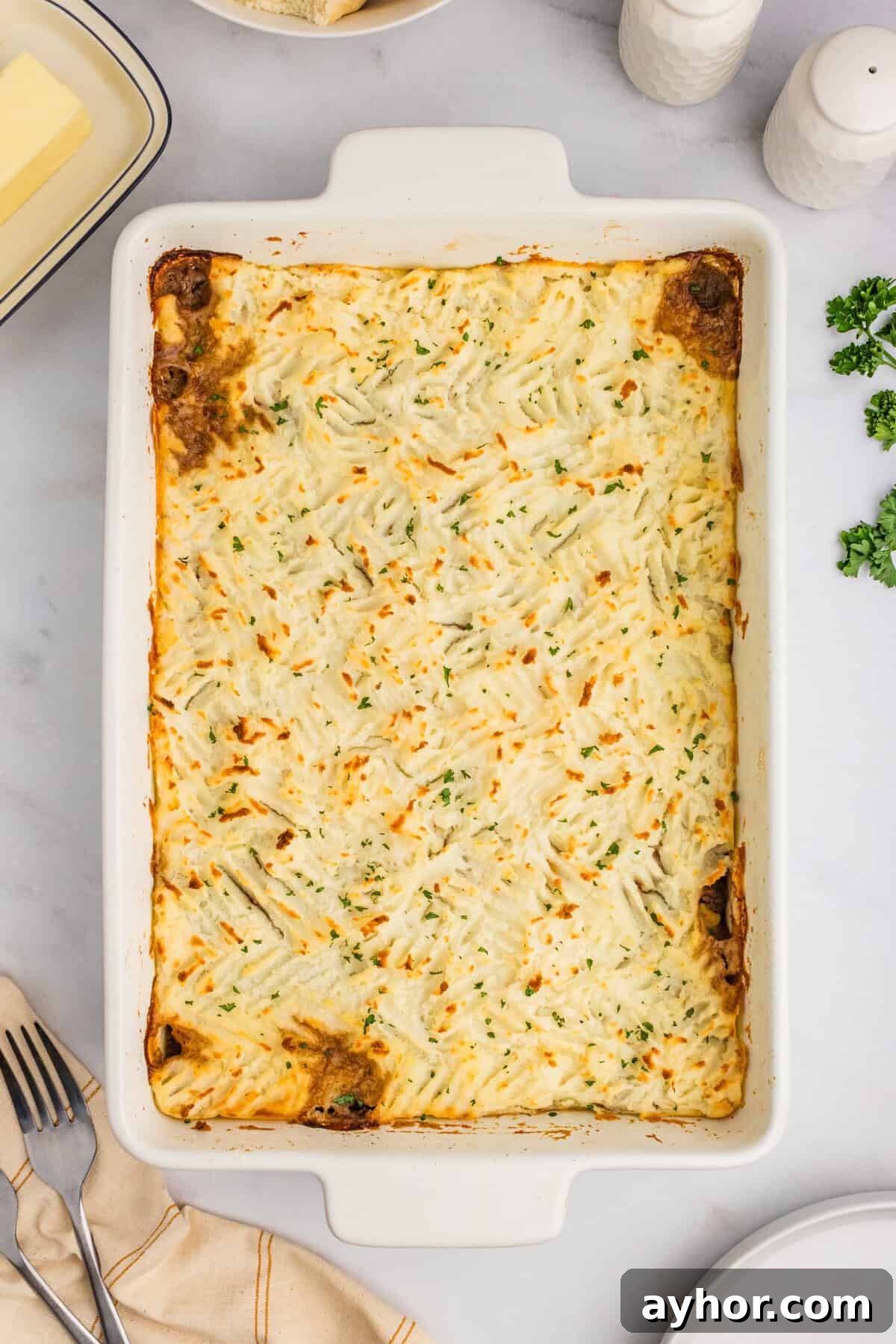 A baked cottage pie in a white casserole dish with a golden-brown mashed potato topping.