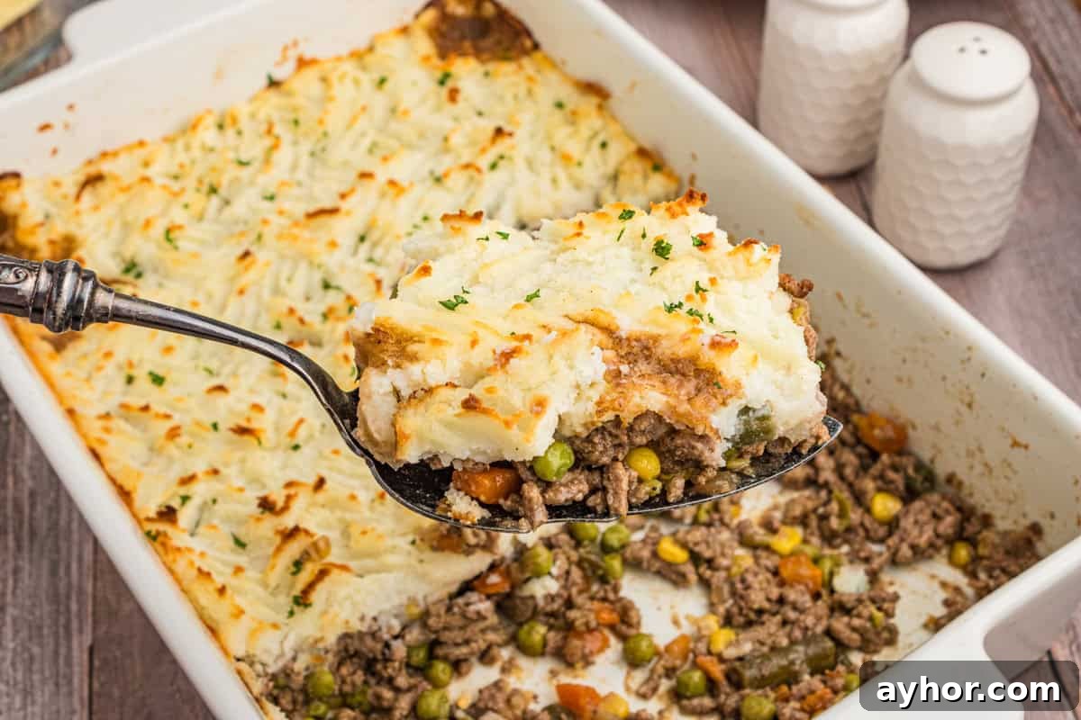 A serving of cottage pie being lifted from a baking dish, revealing the filling underneath.