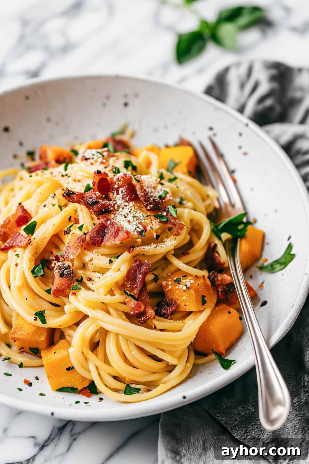 Pumpkin carbonara spaghetti with bacon and herbs.