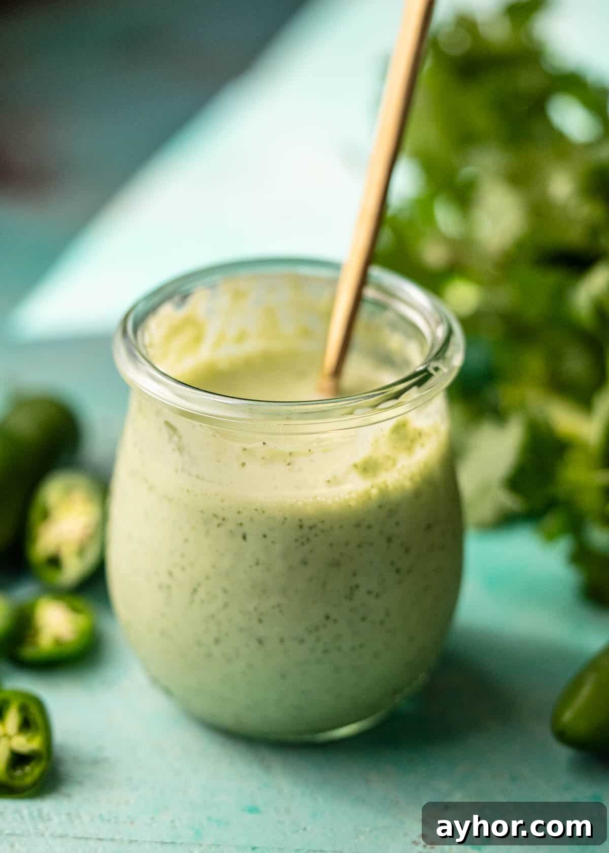 Creamy Jalapeño Ranch Dressing Recipe for Spicy Salads 4 a jar of jalapeno ranch surrounded with chopped jalapenos and fresh cilantro