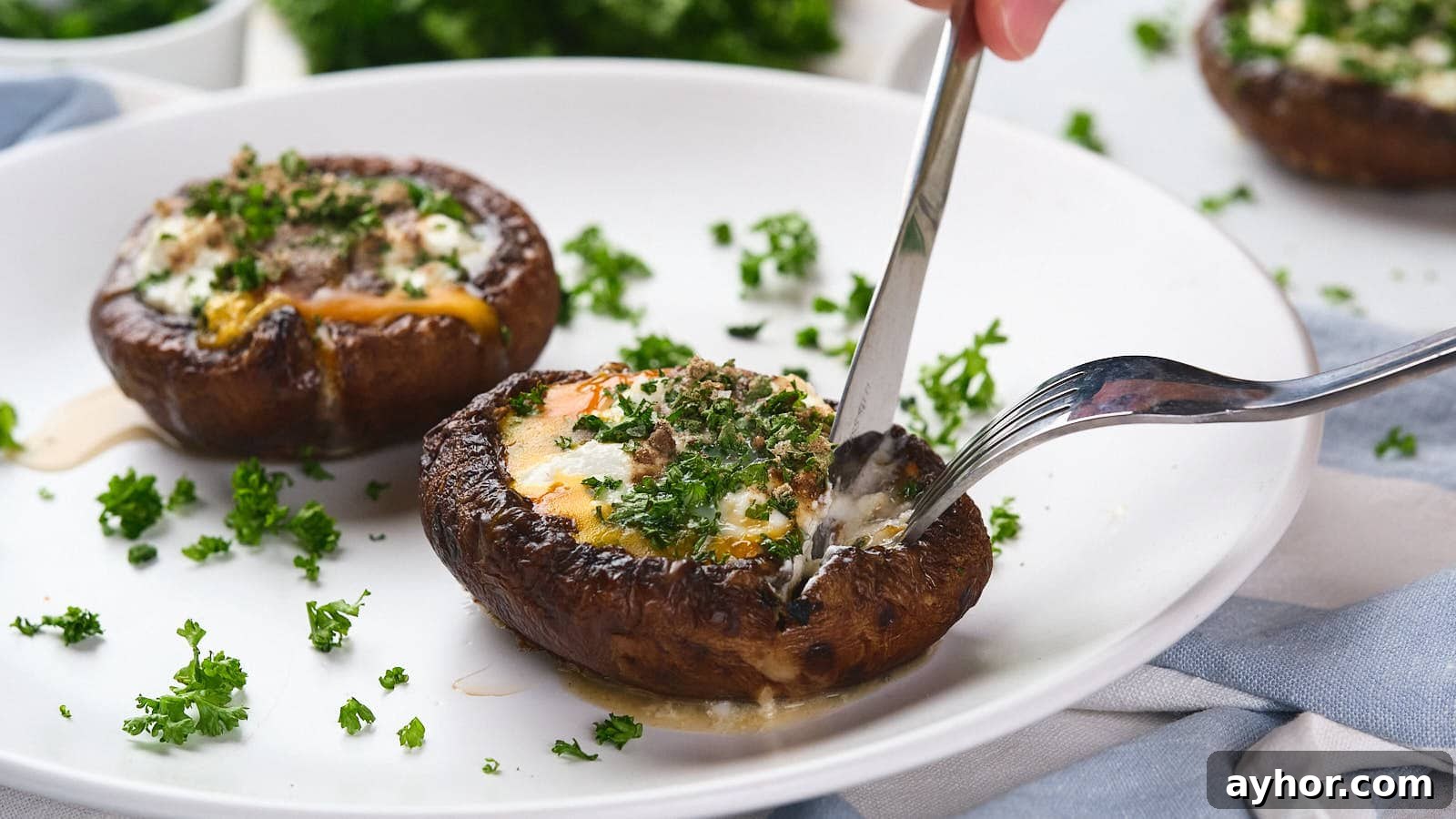 A fork and knife cutting into an egg in mushroom with green garnish visible in the background.