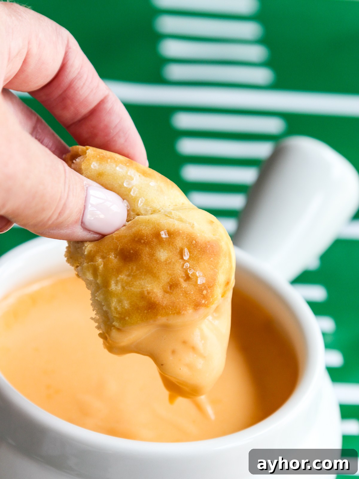 Dipping football pretzel into beer cheese dip