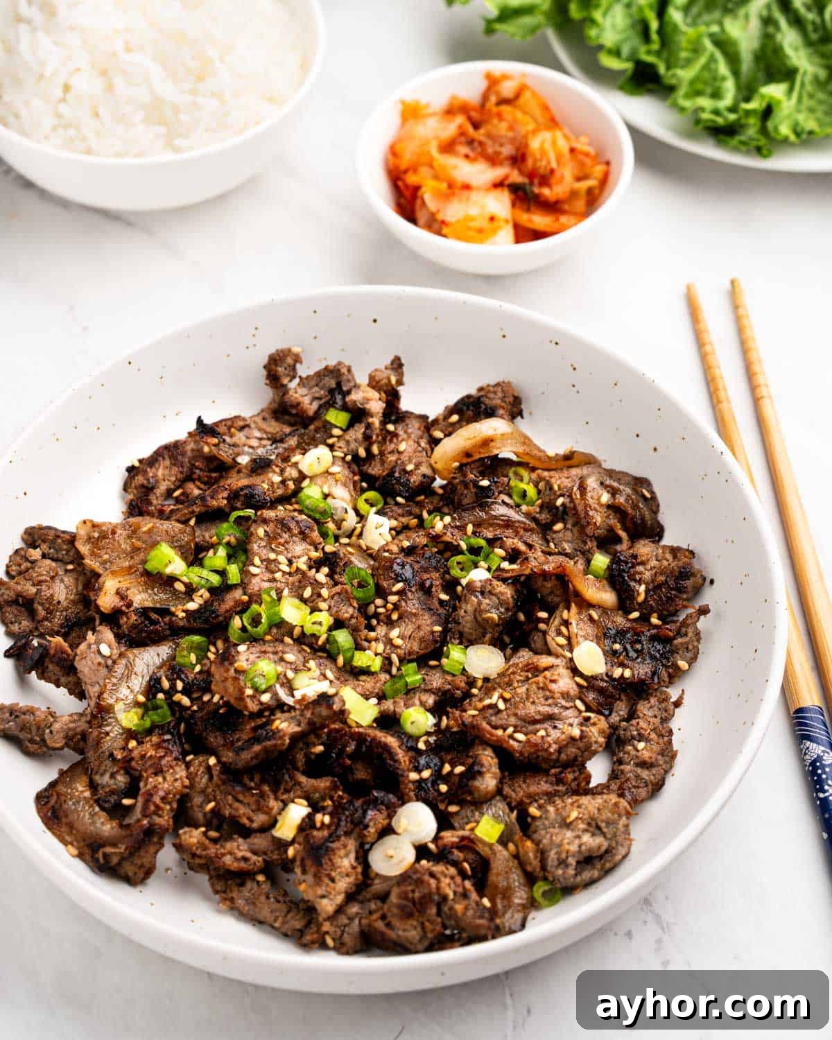 Plate of beef bulgogi topped with sliced green onions and sesame seeds.