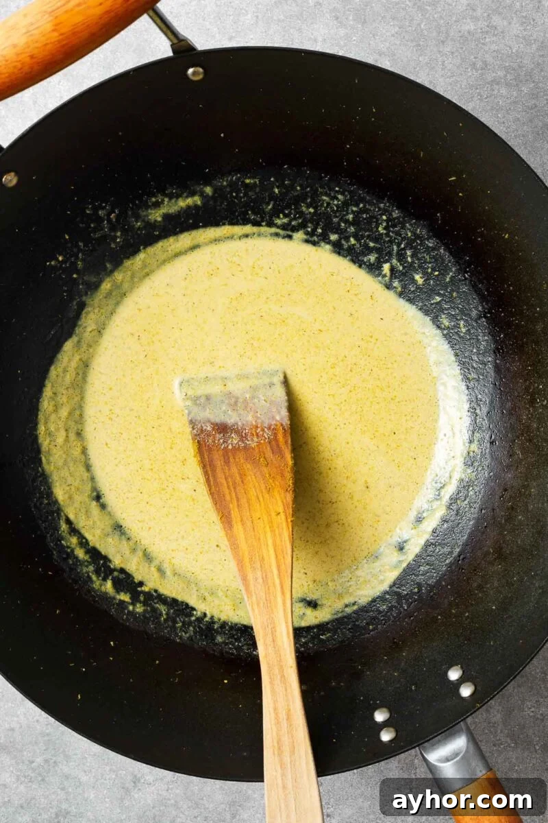 Making green curry sauce with green curry paste and coconut oil.