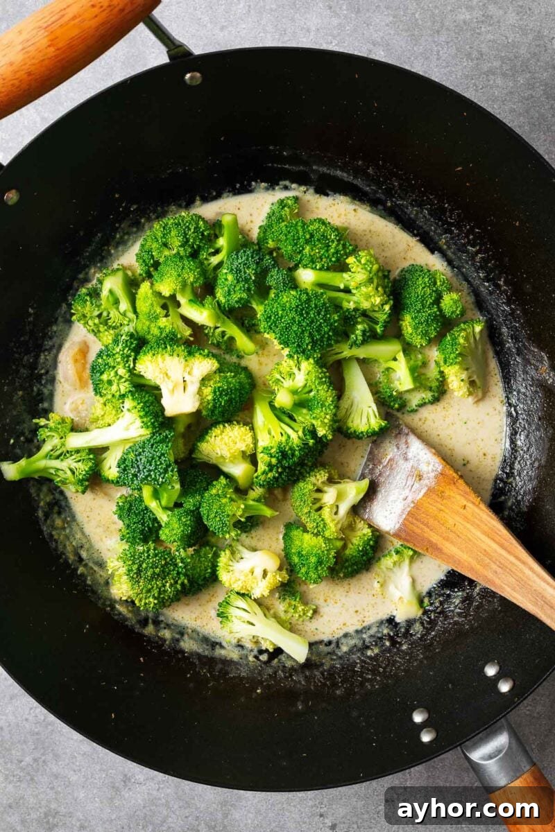 Raw broccoli added to Thai green curry sauce.