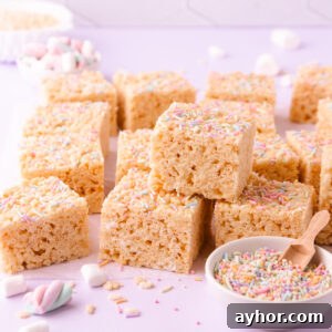 Gluten-Free Rice Krispie Treats Recipe That Really Crisps 11 A stack of gluten free rice krispie treats on a pale purple background with a small bowl of pastel sprinkles.