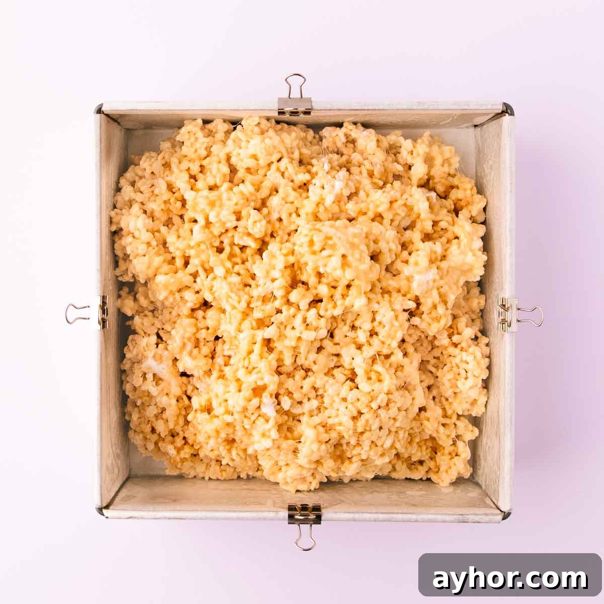 Gluten-Free Rice Krispie Treats Recipe That Really Crisps 8 The rice krispie mixture piled into a baking paper lined square cake pan.