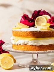 Victoria sponge topped with powdered sugar, lemon slices, and peonies