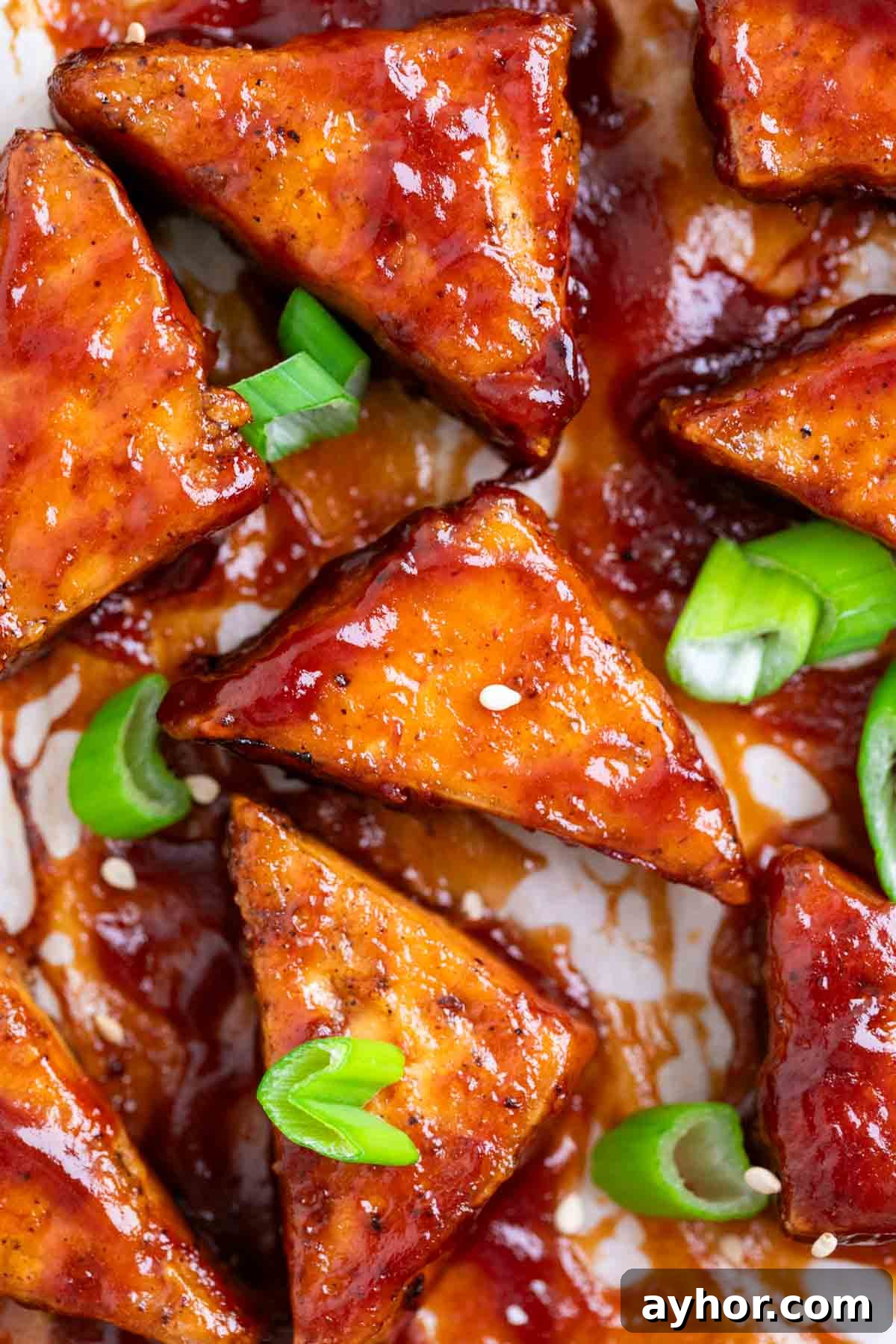 Grilled BBQ Tofu Recipe: Smoky, Glazed Plant-Based Dish 13 Baked BBQ tofu triangles garnished with green onions and sesame seeds